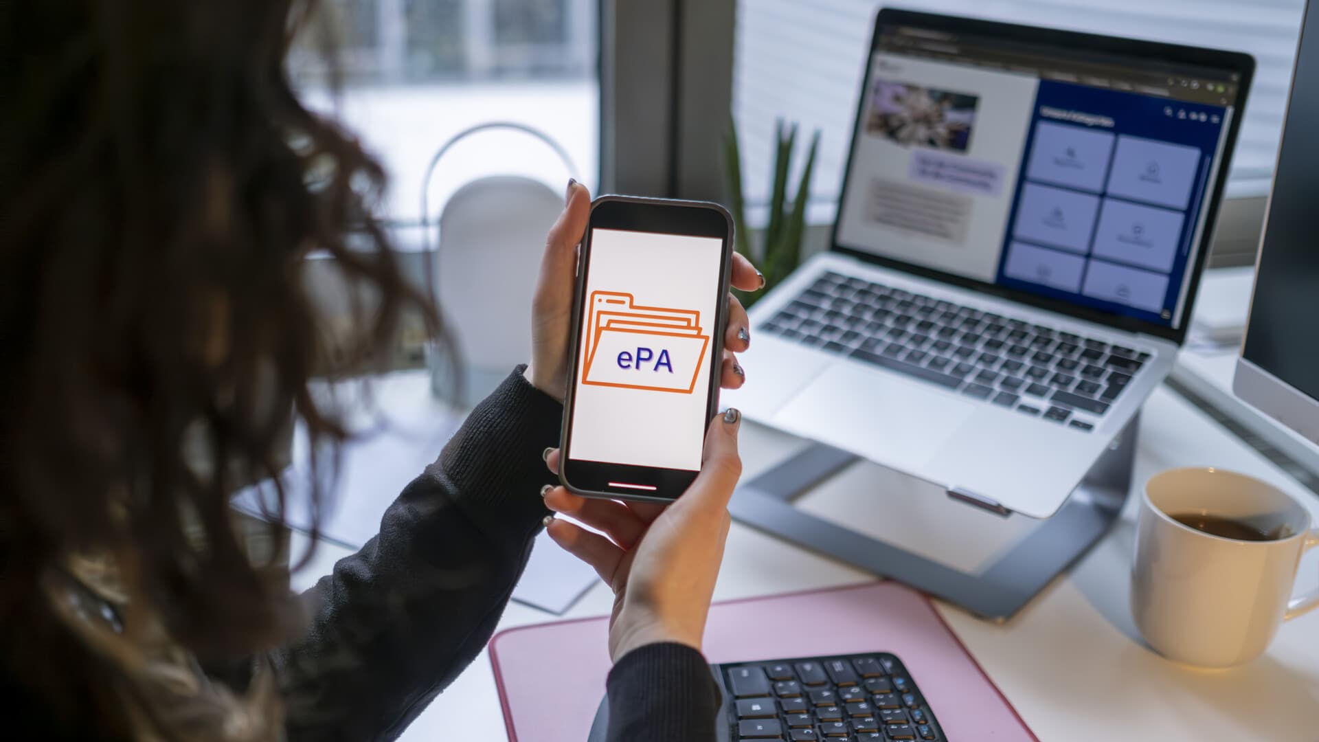 Person schaut auf das Display des Mobiltelefons, auf dem "ePA" steht.